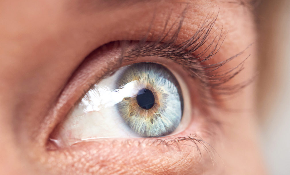 Close-up of a blue eye with detailed iris patterns and surrounding eyelashes.